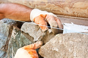 a worker doing commercial masonry restoration for stone walls