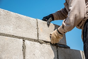 worker doing commercial masonry repair services to a stone wall