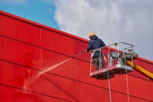 Man performing a Commercial pressure washing on building