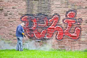 commercial pressure washer removing graffiti on building