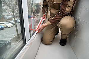 Worker waterproof caulking a window