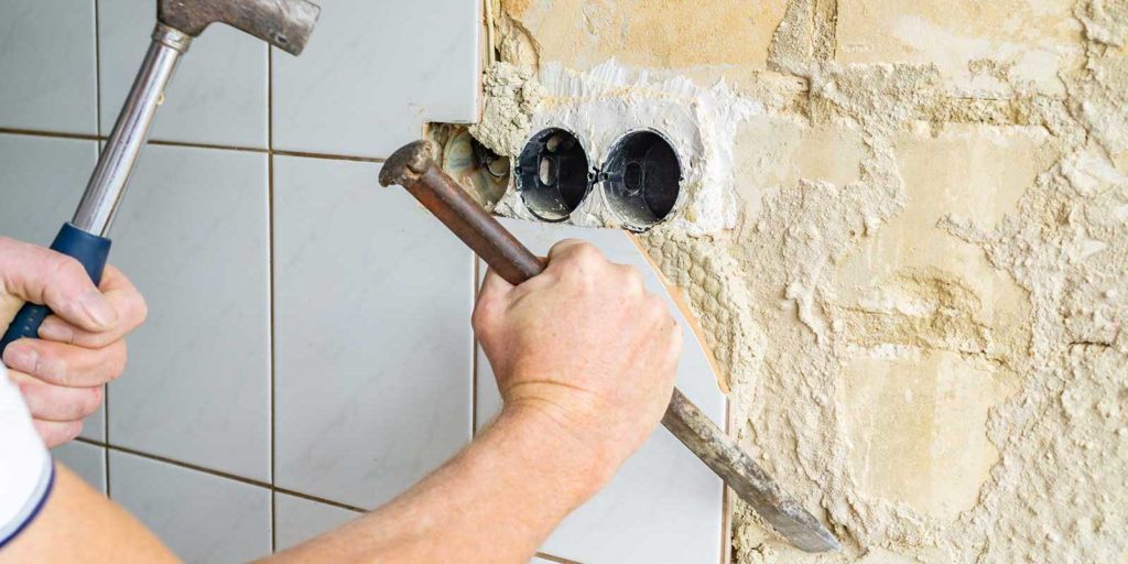Commercial waterproofing contractor removing tile from a wall
