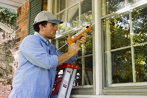 a contractor applying exterior caulking to a residence