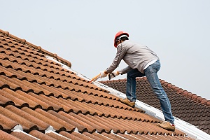a contractor caulking a roof to prevent water damage to a residence