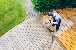 a man powerwashing a deck and making it clean