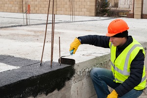 construction worker makes bituminous Waterproofing Company
