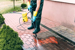 man cleaning red conrete pavement block using Commercial Pressure Washing