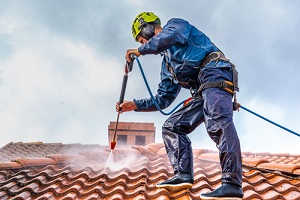 worker Pressure Washing Services on the roof with pressurized water