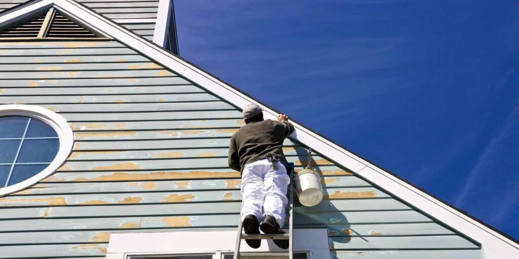 contractor or painter on a ladder doing exterior paint work