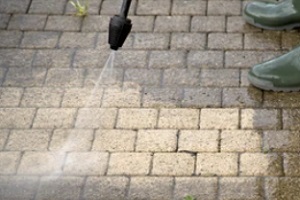 man washing dirty brick floor with power wash