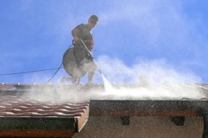 man power washing home roof