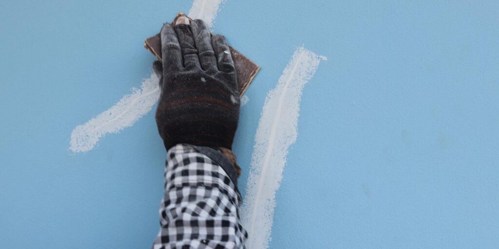 A hand patching wall with the use of white concrete