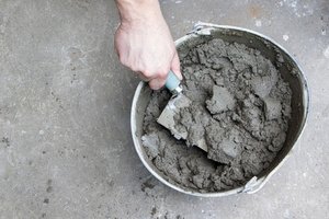 A hand is preparing concrete mix in a bowl with the use of a towel