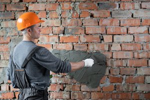 A commercial masonry contractors plastering a brick wall with cement mortar