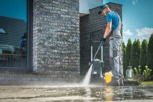 A man power washing the building and road surrounding it