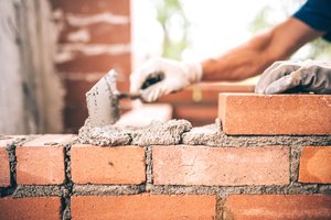 A worker building a brick wall with the help of a trowel