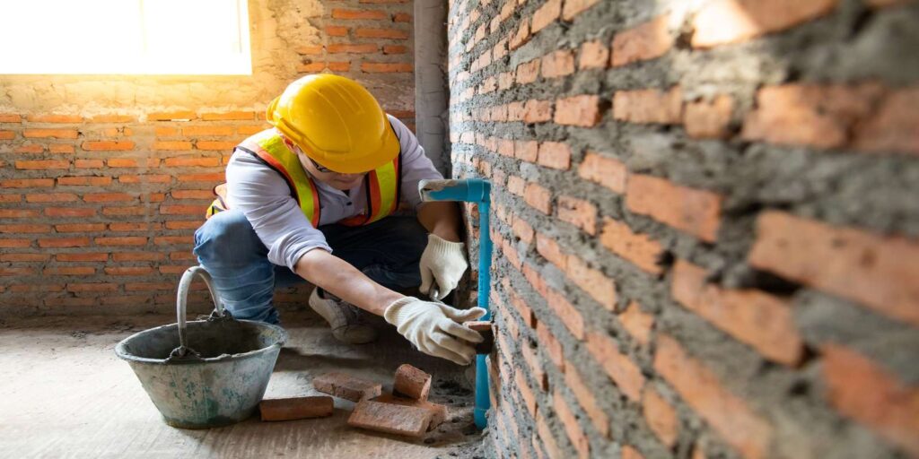A commercial masonry contractor checking a brick wall