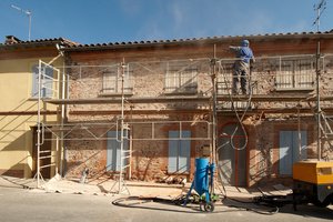 Two people scaffolding a wall for commercial masonry work