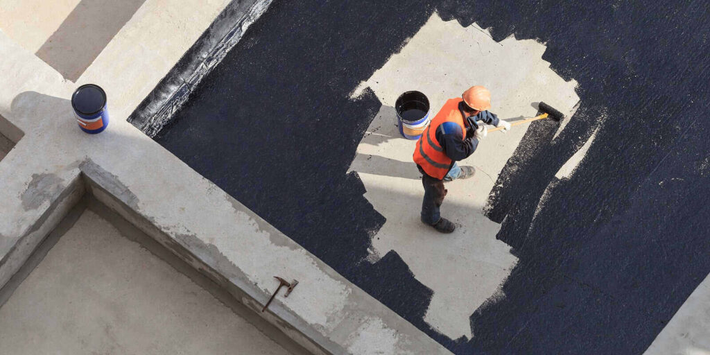 NJ worker in overalls applies an insulation coating on the concrete surface