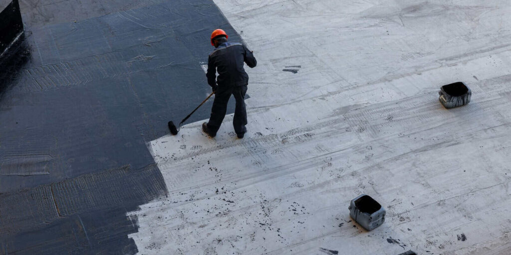 DE waterproofing worker applies sealant to the foundation