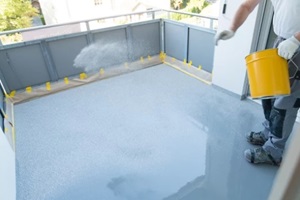 construction worker renovates balcony floor and spreads chip floor covering on resin and glue coating before applying water sealant