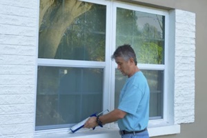 homeowner caulking window with a caulk gun
